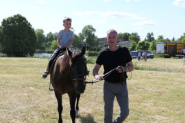 Mężczyzna prowadzi konia, na którym siedzi mały chłopiec