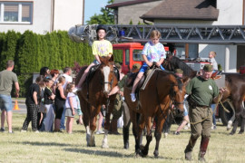 Dwa konie, na których siedzą dzieci. Konie prowadzi mężczyzna 