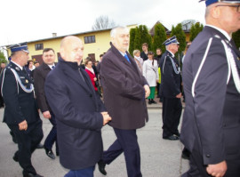 Mężczyźni, jedni w mundurach, inni w cywilnych ubraniach idą w defiladzie 