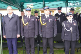 Czterech mężczyzn stojących w szeregu. Trzech z nich ubranych jest w mundury, jeden jest w cywilnym ubraniu