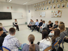 Kobieta-trenerka prowadzi rozmowę w kręgu z uczniami w klasie