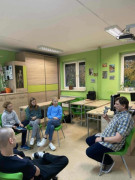 Prowadzący trzyma w ręku pacynkę i rozmawia z uczniami siedzącymi w kręgu