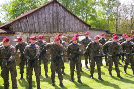 Grupa żołnierzy w mundurach moro i czerwonych beretach na głowie. Każdy z nich w ręku trzyma broń