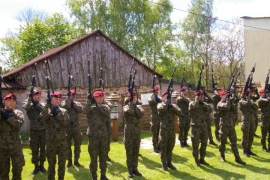 Grupa żołnierzy w mundurach moro. Na głowach wszyscy mają czerwone berety. W dłoniach trzymają długą broń