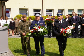 Trzech mężczyzn w mundurach składa kwiaty