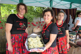 Trzy kobiet w kolorowych strojach: członkinie KGW "Makowe Panienki" prezentują konkursową potrawę: pierogi