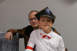Mężczyzna i chłopiec. Chłopiec ubrany jest w białą koszulę i żołnierską czapkę 
