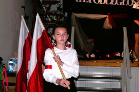 Dziewczynka w galowym stroju trzymająca biało-czerwoną flagę 