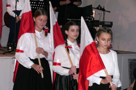 Dziewczynki w galowych strojach. Każda z nich trzyma biało-czerwoną flagę 