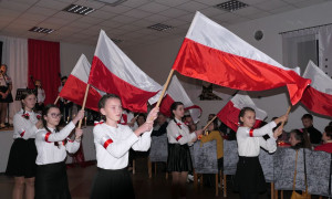 Dziewczynki w galowych strojach. Każda z nich trzyma biało-czerwoną flagę 