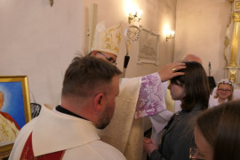 Biskup udziela bierzmowania w młodej dziewczynie