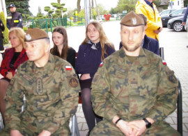 Grupa osób w tym wojskowi siedzi na krzesłach 
