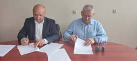 Dwóch mężczyzn siedzących za stołem i podpisujących dokumenty