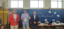Nagrodzony uczeń pokazuje dyplom. Towarzyszą mu dwie osoby: dyrektor szkoły w Płoszowie oraz wójt Gminy Radomsko
