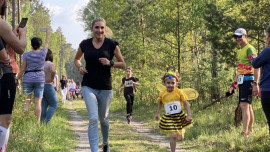 Dorosła kobieta i mała dziewczynka w stroju pszczółki podczas biegu leśnymi ścieżkami 