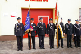 Grupa mężczyzn w mundurach. Dwóch z nich trzyma sztandary