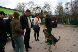 Przedstawiciele gminy rozmawiają z pracownikiem schroniska trzymającym psa