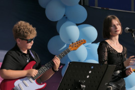 Chłopiec grający na gitarze. Obok stoi dziewczyna 