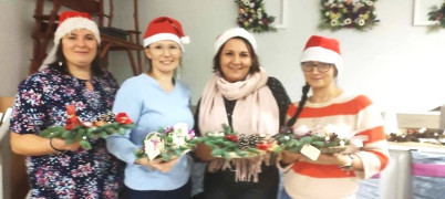 Cztery kobiety w czapkach mikołaja prezentują świąteczne stroiki 