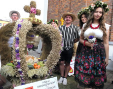 Wieniec dożynkowy oraz osoby przy nim stojące 