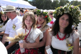Dwie kobiety i dziewczynka siedzą obok siebie. Kobiety mają na głowie wianki 