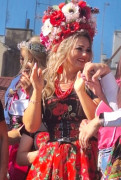 Uśmiechnięta kobieta w kolorowym stroju i wianku na głowie 