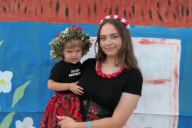 Młoda dziewczyna trzyma na ręku małą dziewczynkę 