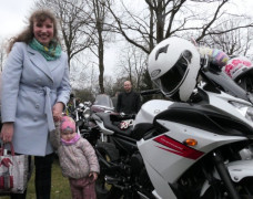 Kobieta z małym dzieckiem stoi przy motocyklu 