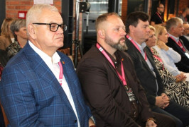 Grupa osób siedzi na krzesłach podczas spotkania obok siebie