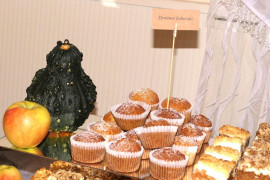 Ciasta i babeczki stojące na stole ozdobionym m.in. małymi dyniami 