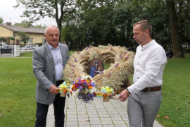 Mężczyźni niosą wieniec dożynkowy 