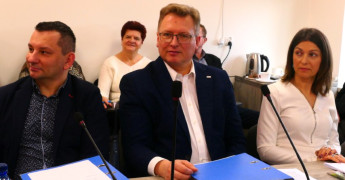 Kobieta i dwaj mężczyźni siedzący za stołem prezydialnym 