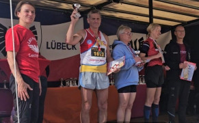 Grupa ludzi w strojach sportowych. Jeden z mężczyzn trzyma w ręku puchar