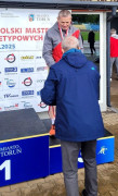Zawodnik stoi na podium. Odbiera gratulacje 