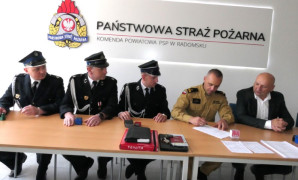 Pięciu mężczyzn siedzi za stołem. Trwa podpisywanie umowy