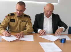 Dwaj mężczyźni siedzą obok siebie. Moment podpisywania umowy