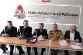 Pięciu mężczyzn siedzi obok siebie. Trwa podpisywanie dokumentów 