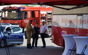 Wóz strażacki, samochód policyjne i trzy osoby stojące w ich pobliżu 