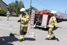 Strażacy rozciągają węże gaśnicze 