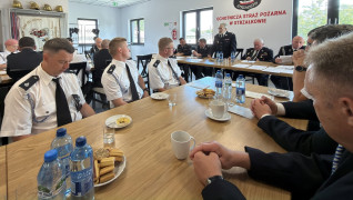 Strażacy ochotnicy podczas Walnego Zebrania. Uczestnicy spotkania siedzą za stołami 
