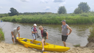 Rzeka, kajak i osoby stojące przy nim 