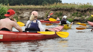 Osoby płyną kajakami po rzece 