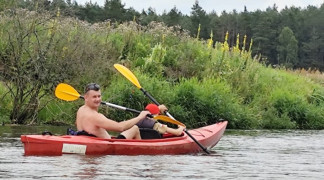 Mężczyzna płynie z chłopcem kajakiem po rzece 