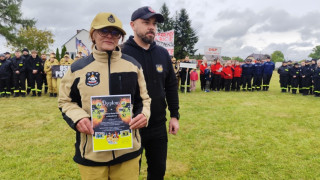 Druhna trzyma w ręku dyplom. Obok druhny stoi mężczyzna 