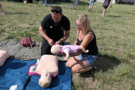 Strażak pokazuje na fantomie zainteresowanej kobiecie jak udzielić pierwszej pomocy dziecku 