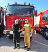 Dwóch mężczyzn z strojach strażaków n tle samochody pożarniczego