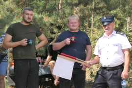 Trzej panowie. Jeden trzyma chorągiewkę 