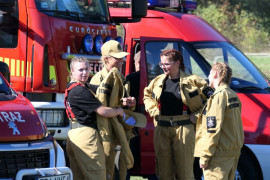 Grupa strażaków stoi obok wozu bojowego