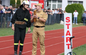Dwaj strażacy stoją na murawie stadionu 