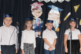 Czwórka dzieci w granatowych biretach obok siebie